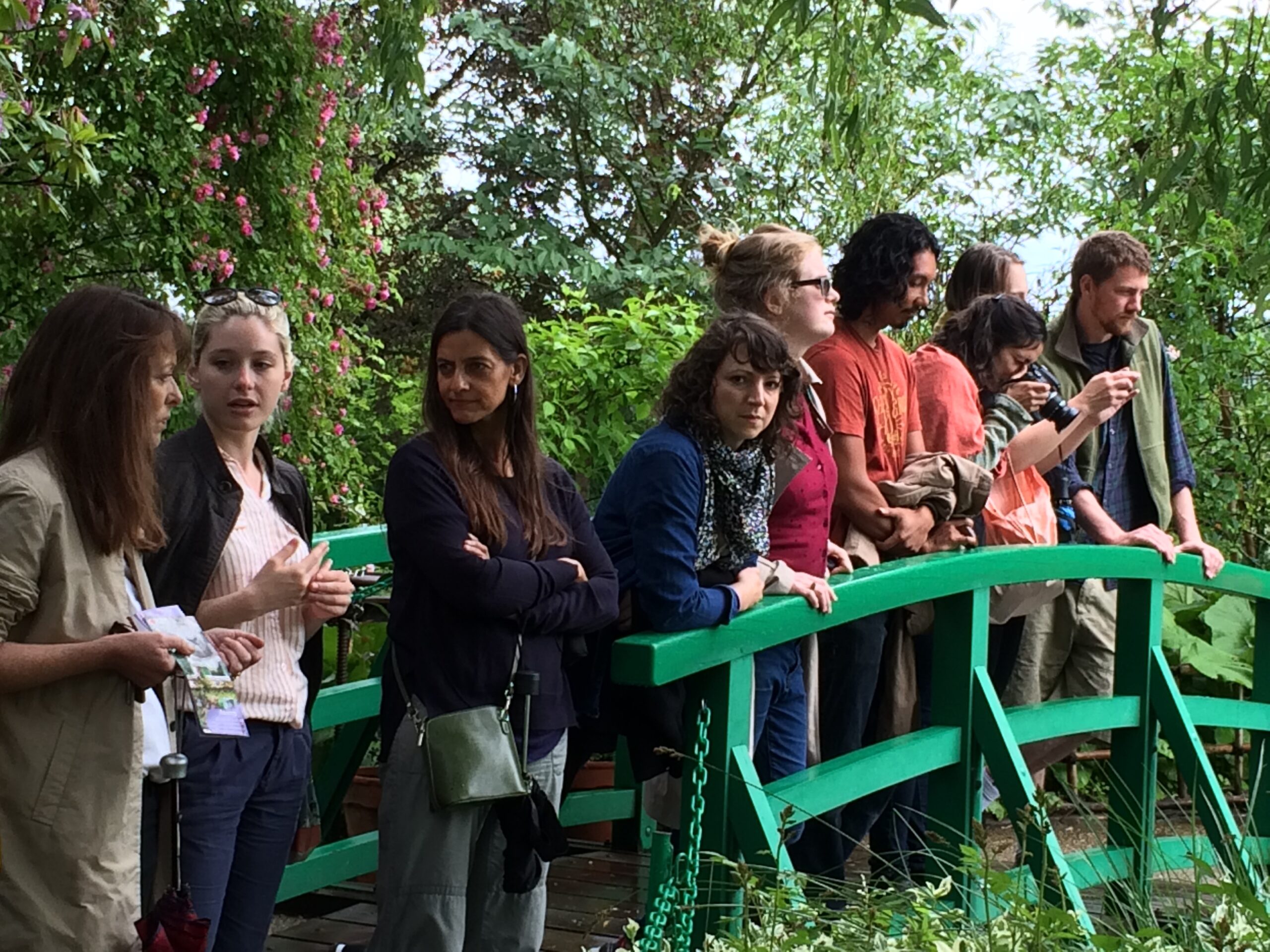 A group of people on a small bridge in Monet's garden viewing the scenery and taking photographs.
