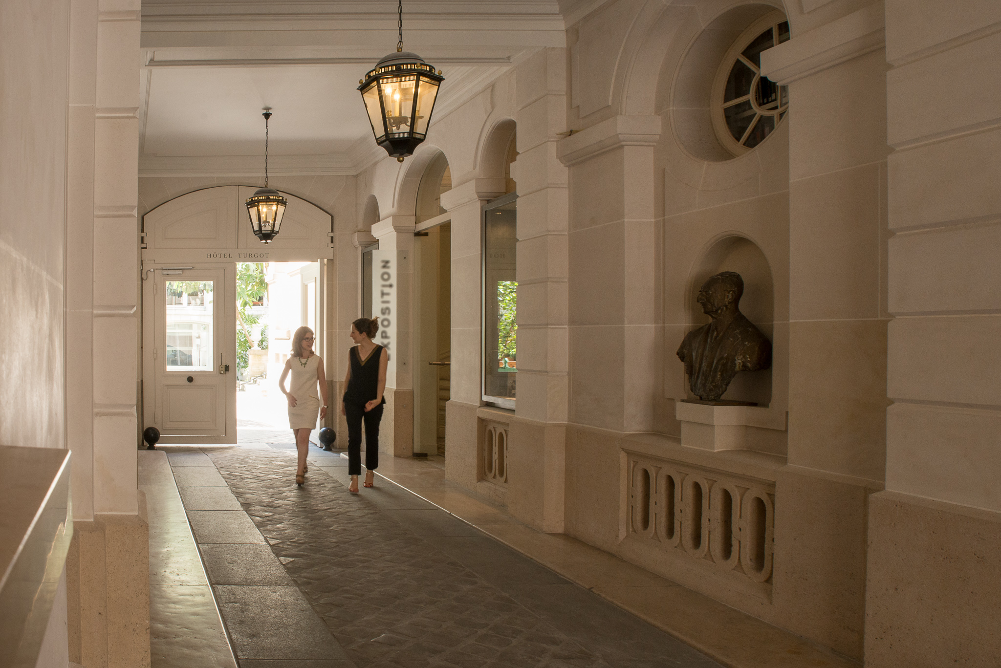 Two people walk down a vestibule inside a building in Paris.