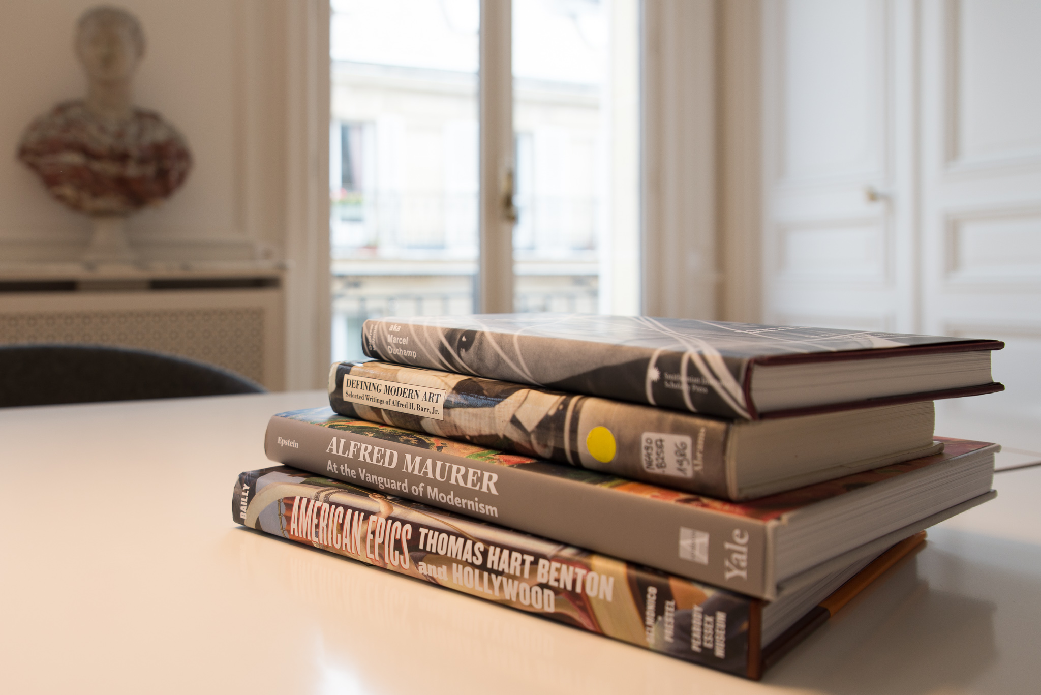 A stack of four books on a white table.