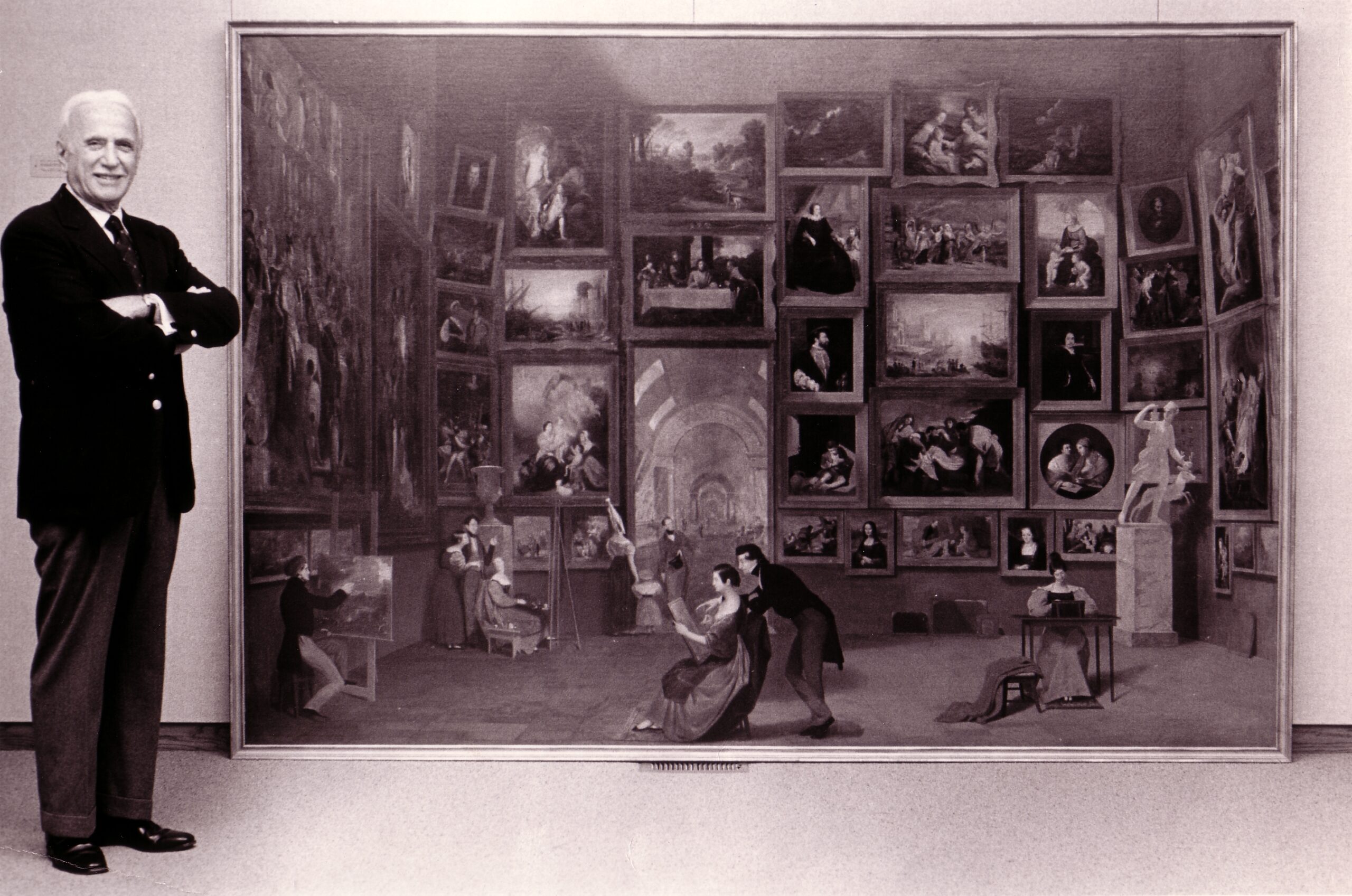 Daniel J. Terra stands next to a large painting set on the ground and leaning against a wall.