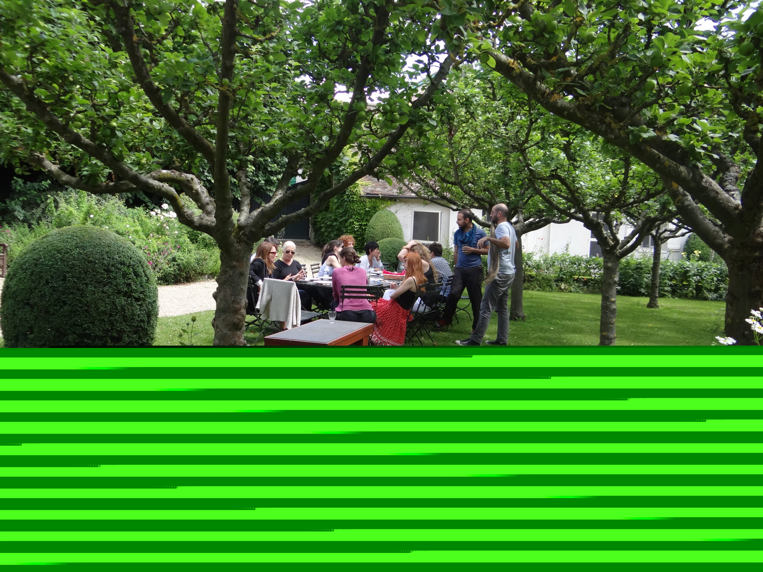 A group of people seated at a table in a garden.