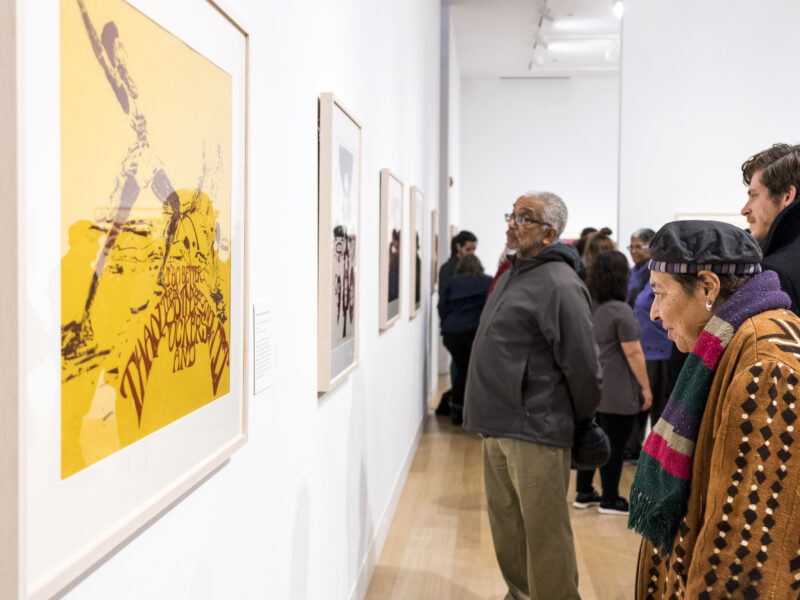 Visitor looking at a yellow painting installed on a white wall.