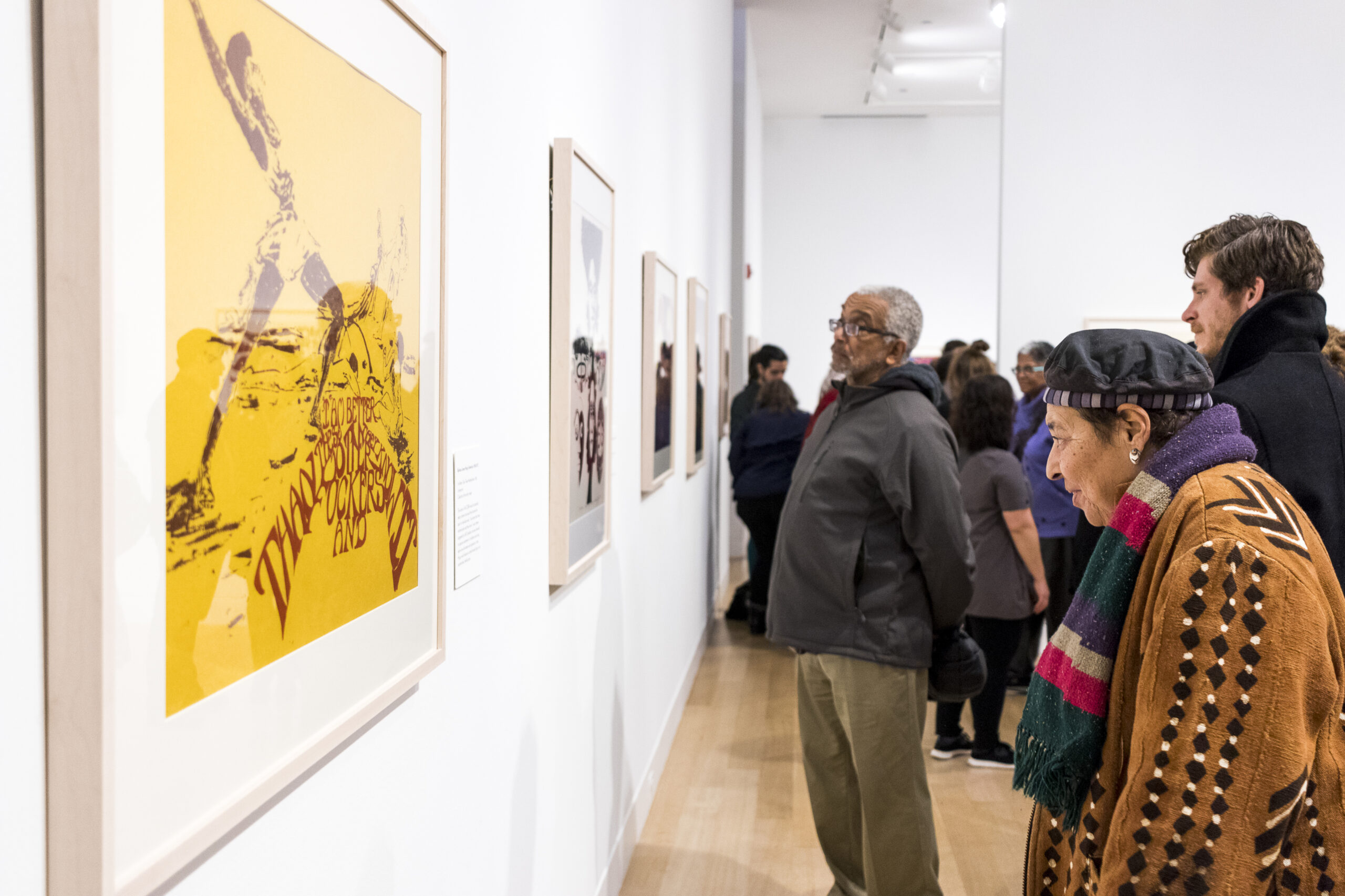 Visitor looking at a yellow painting installed on a white wall.