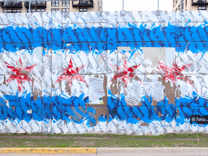 Photo of graffiti on a wall created with types forms. The graffiti resembles the Chicago flag. There are white and blue horizontal stripes with four red stars in the center.