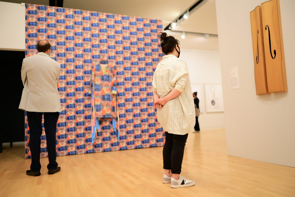 Three people in a museum gallery look at contemporary art objects.