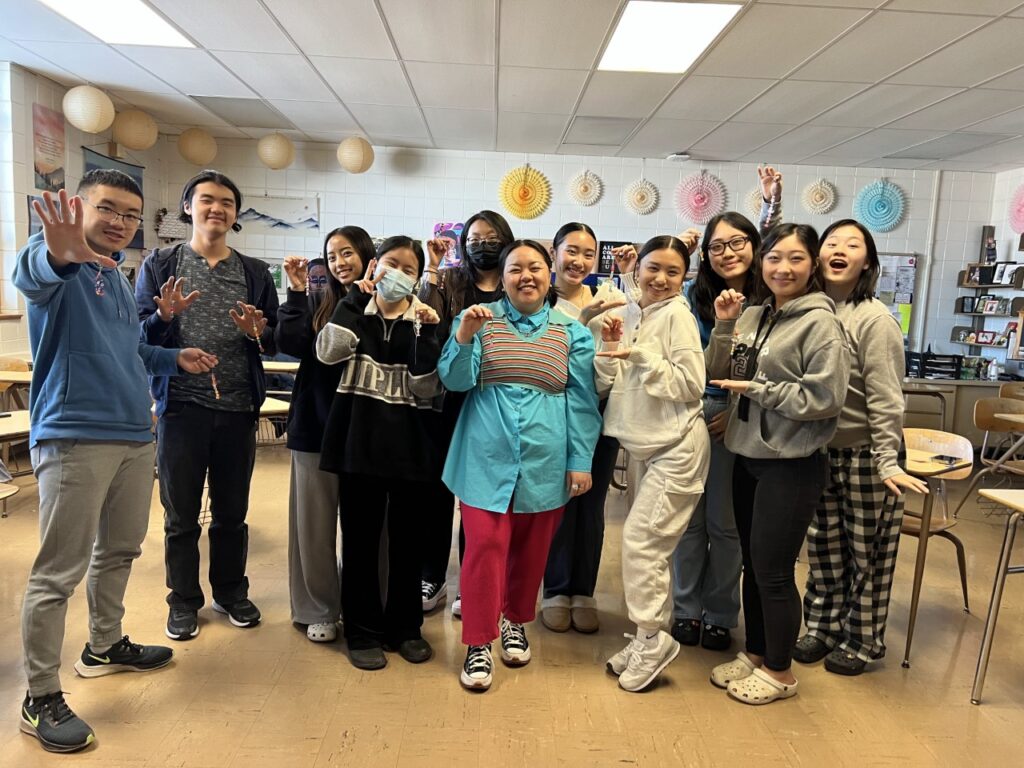 A group of people standing in a classroom, smiling.