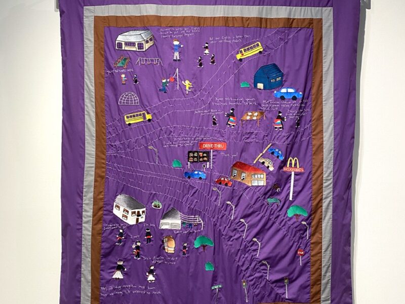 A purple quilt with embroidered imagery titled Becoming White, by artist Ger Xiong.