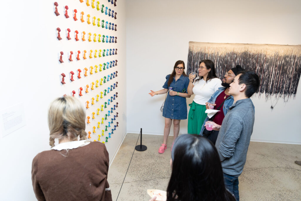 A group of people stand in front of an artwork in a gallery.