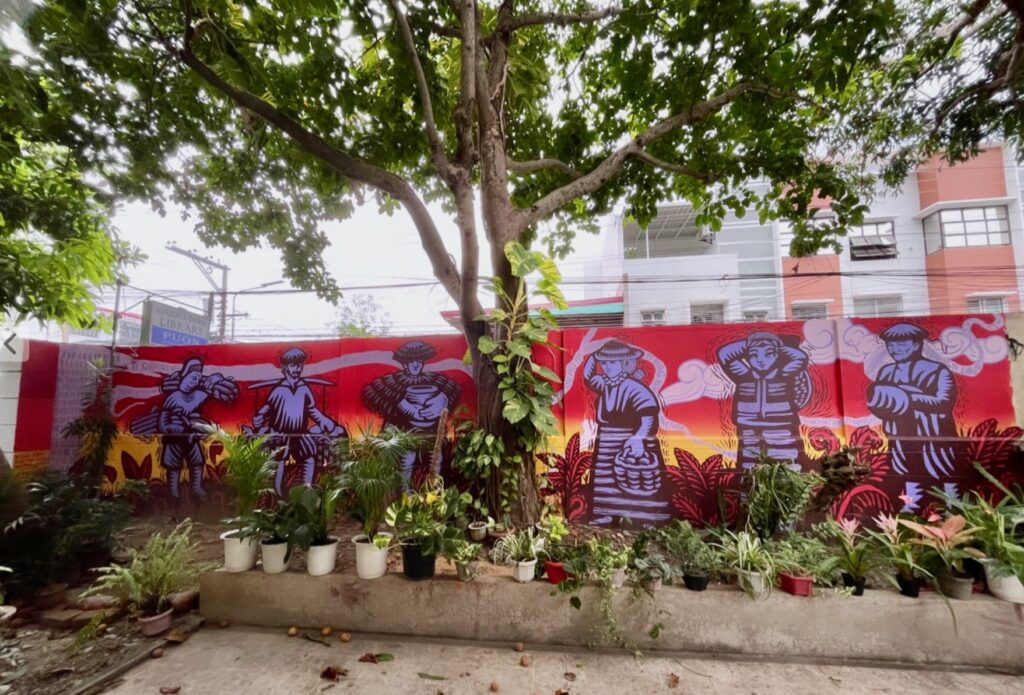 Red and grey mural outside under a tree.