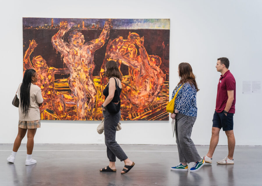 A group of people looking at a painting on a wall as they walk by at an exhibition.
