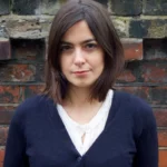 A headshot of person with a blue sweater looking directly into the camera.