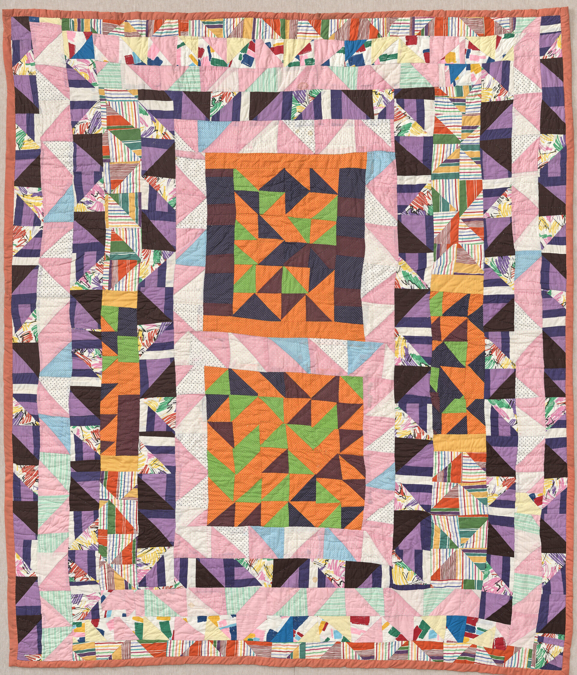 Multi-colored quilt with shades of orange, pink, green, blue, and black.