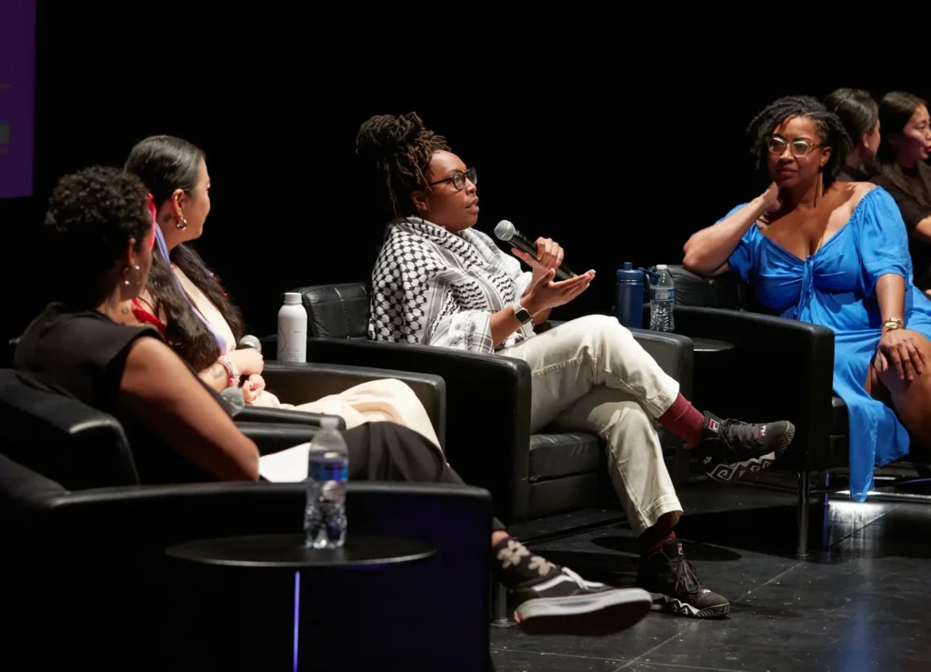 Image of people on stage sitting with microphones.