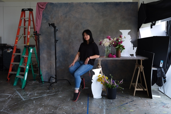 A person sitting, flowers and a ladder on either side.