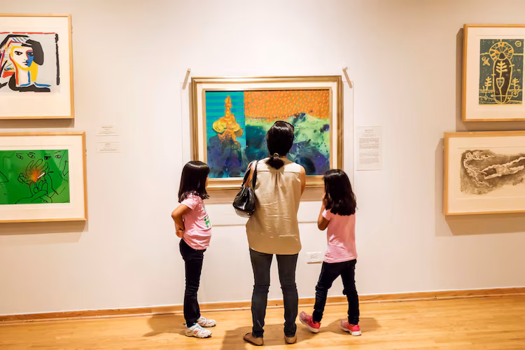 Exhibition view of people admiring an artwork on the wall.