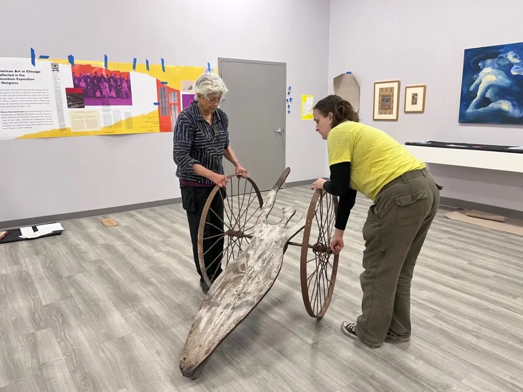 Exhibition view of people near an art object.