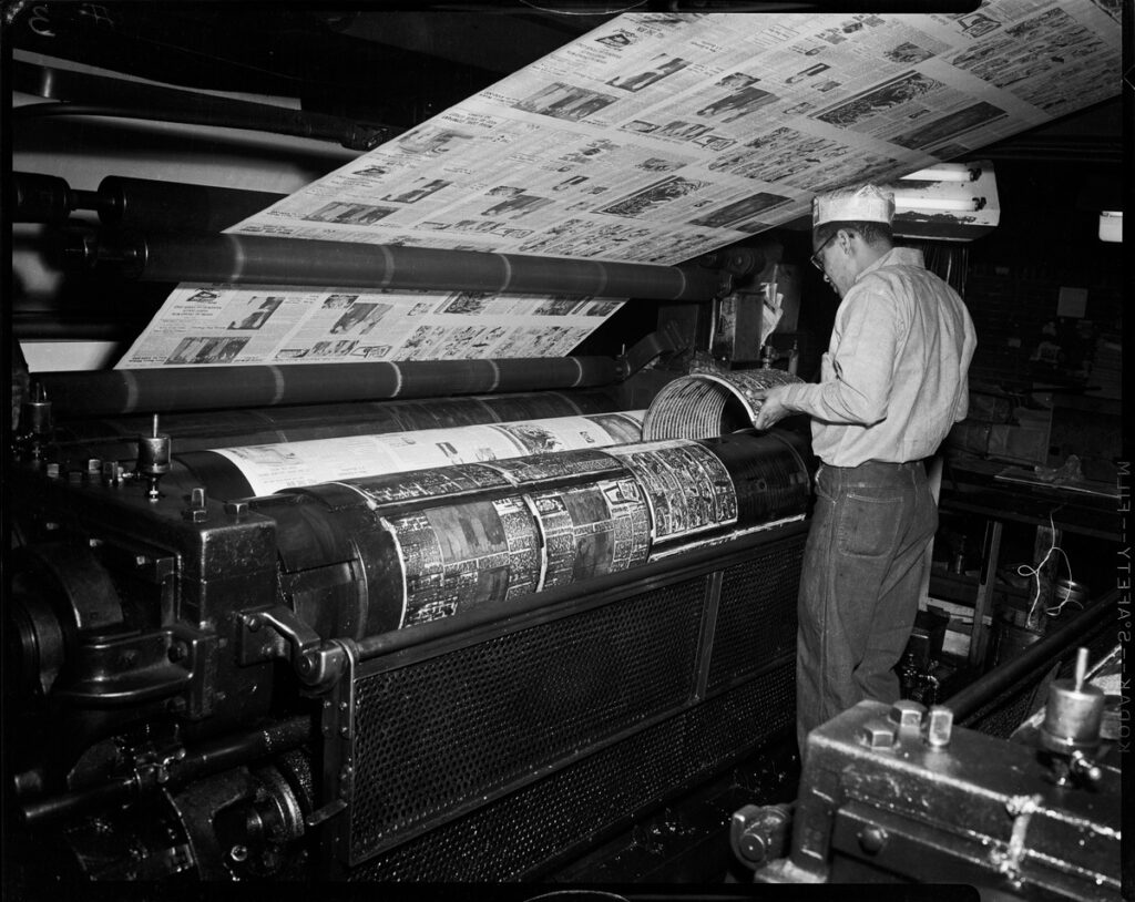 Black and white image of a person operating a printing press machine