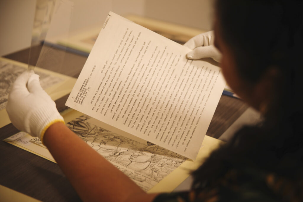 Person with white gloves holding an archival document.
