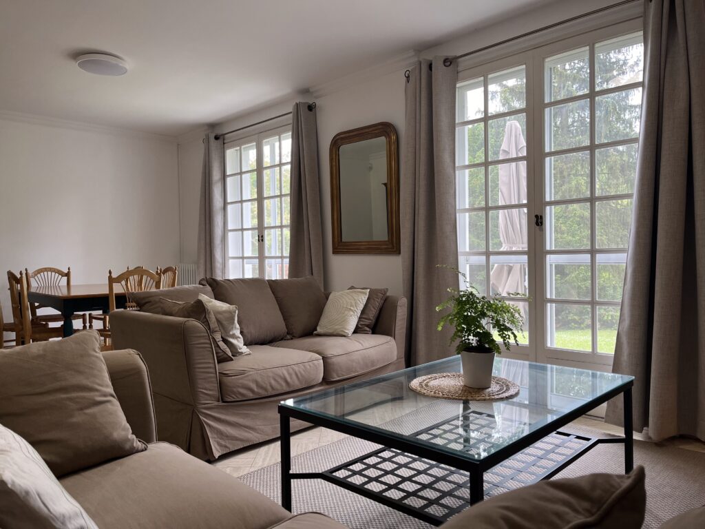 Hervieux House living room with two large windows, couches, and a coffee table.