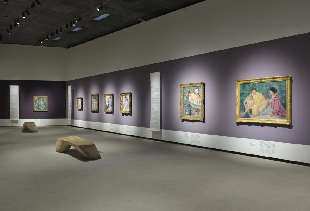 Many paintings hanging in a row on a purple wall.