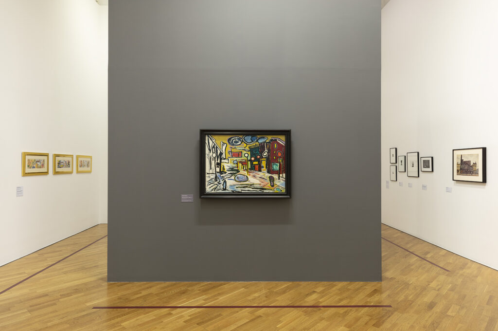 Colorful, abstract painting hanging on a gray wall.