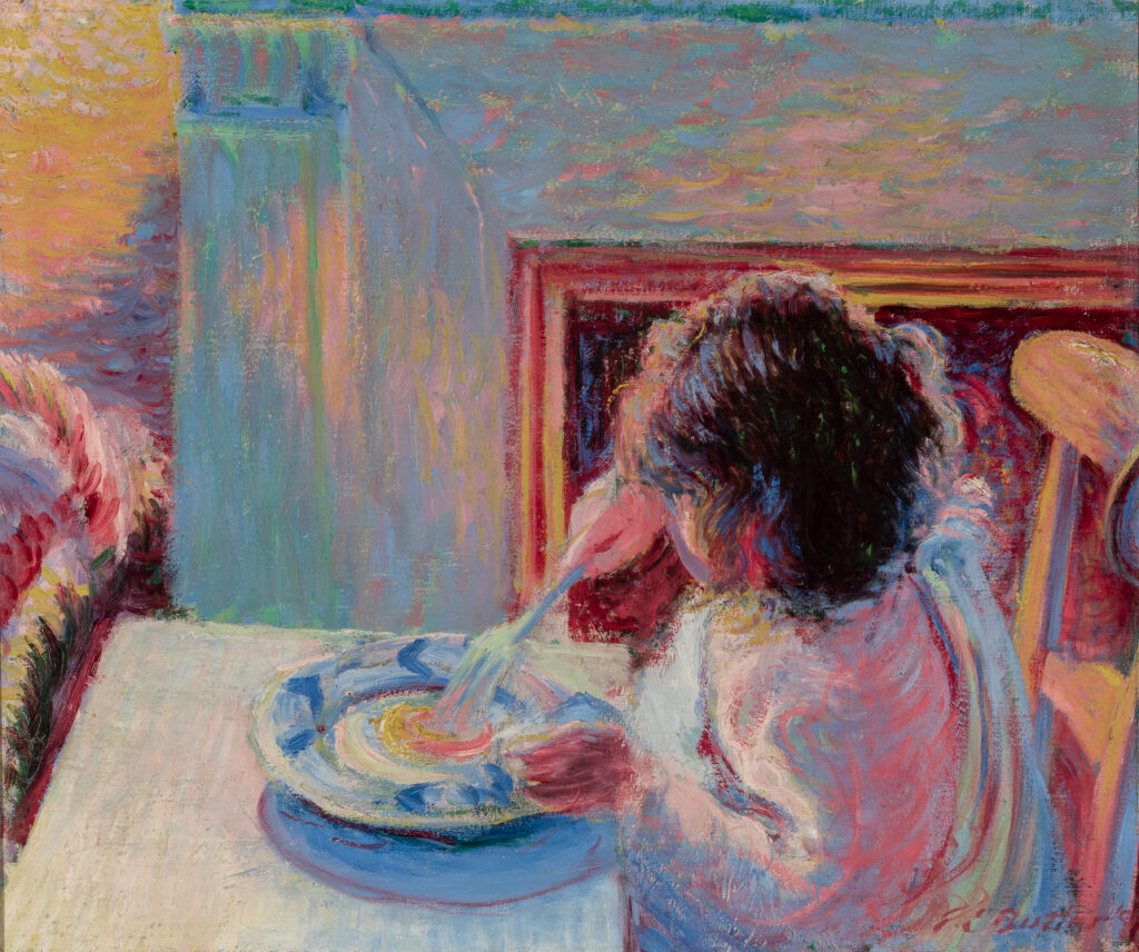 A child sitting at a table uses a fork to eat food from a plate.