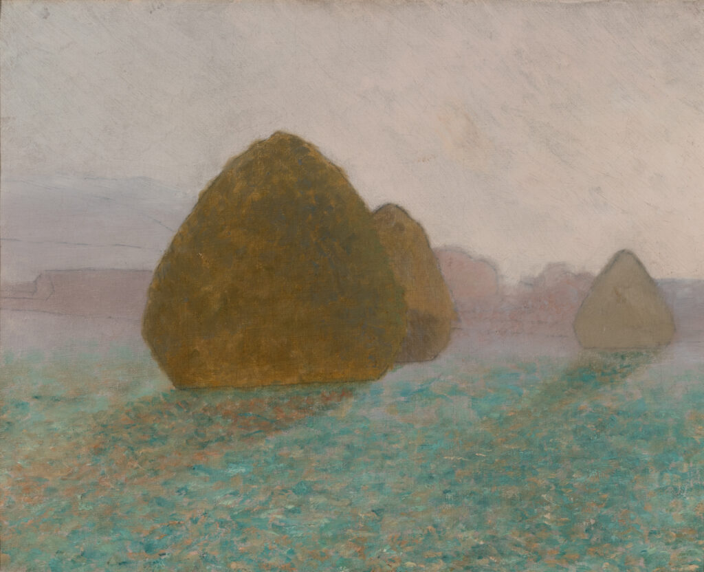 Three haystacks in a green field. It is a misty or foggy day.