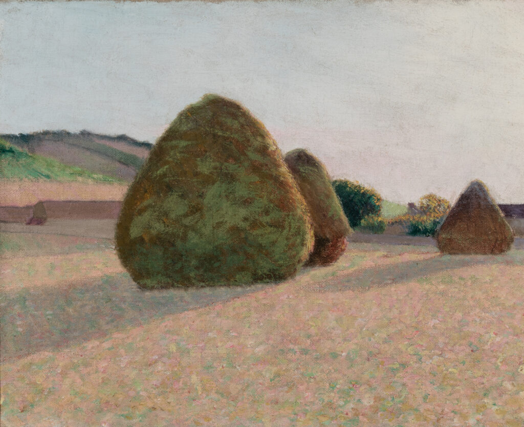 Three haystacks in a field. There are long shadows behind the haystacks.