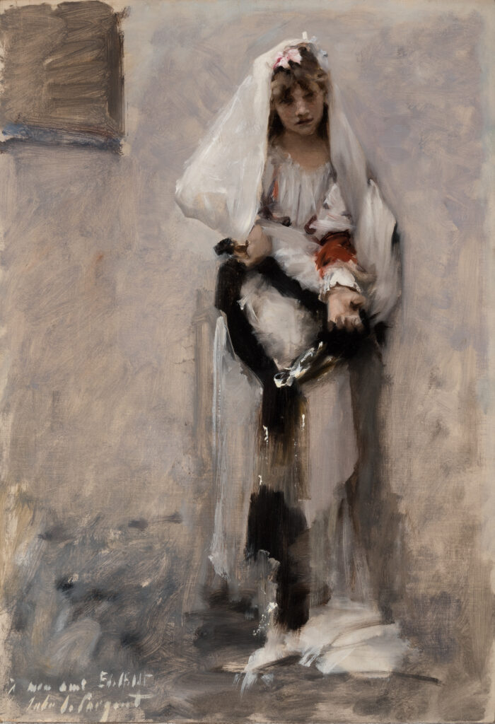 A girl in a white dress stands near a wall and holds out her left hand.