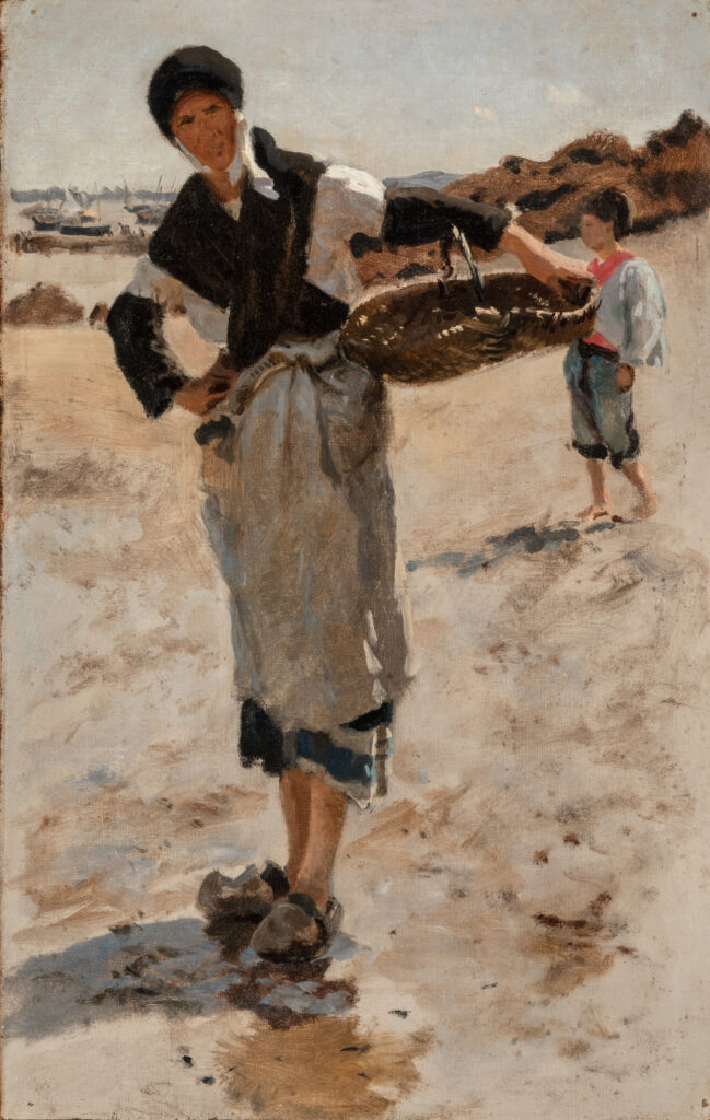 A woman carrying a basket standing on a beach.