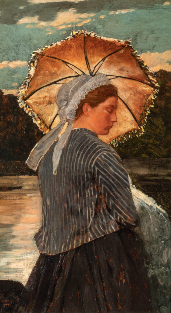 A woman stands under an umbrella.