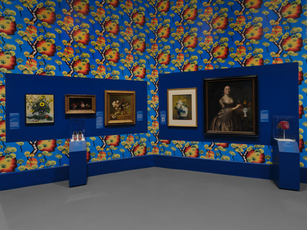Room with flowers on the wallpaper and art hanging on the walls.