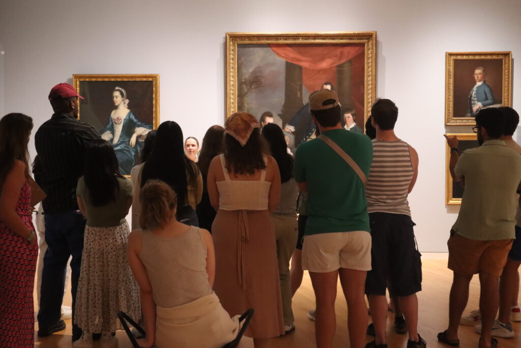 A group of people look at paintings in a gallery.