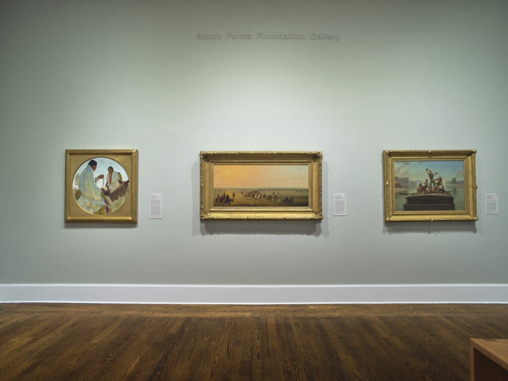A photograph of three paintings on a gallery wall.