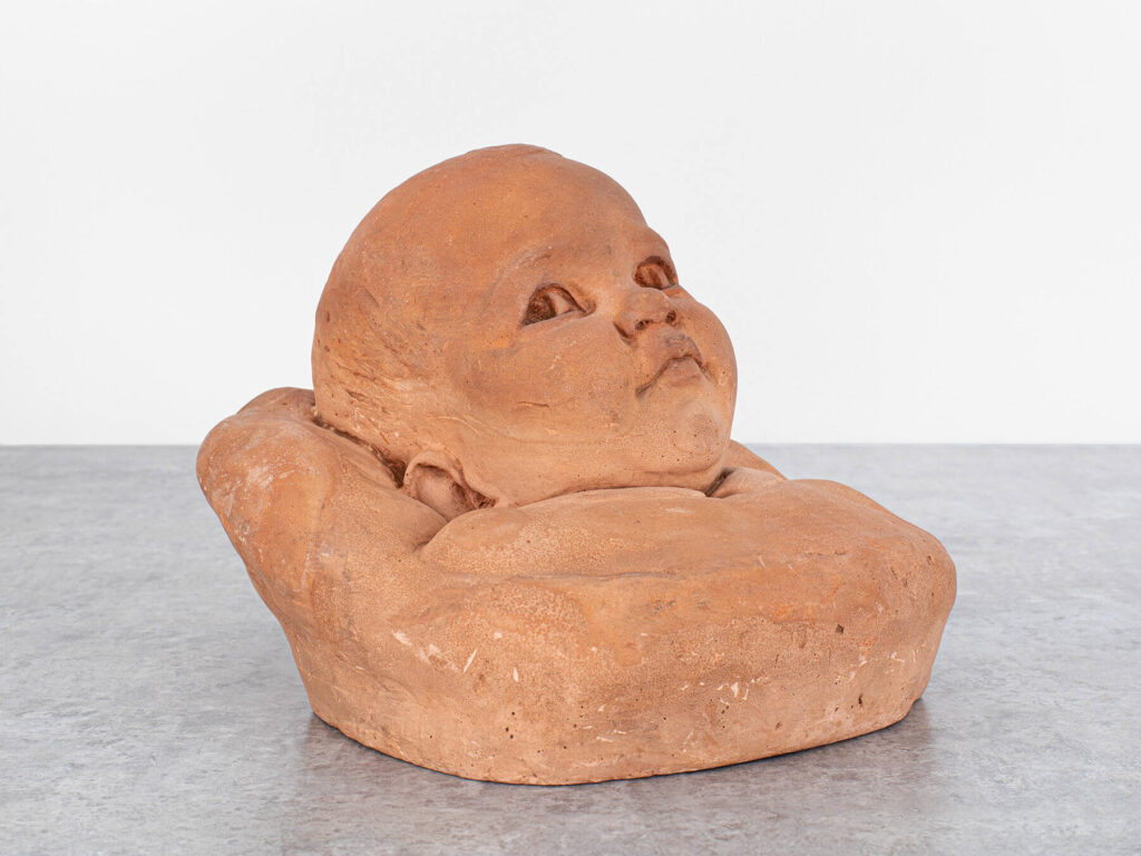 Terracotta bust of a baby's head.