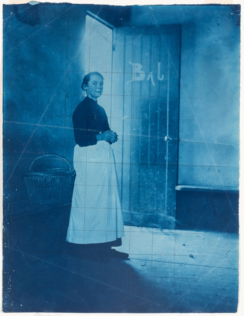 A photograph of a woman standing in front of an open doorway.