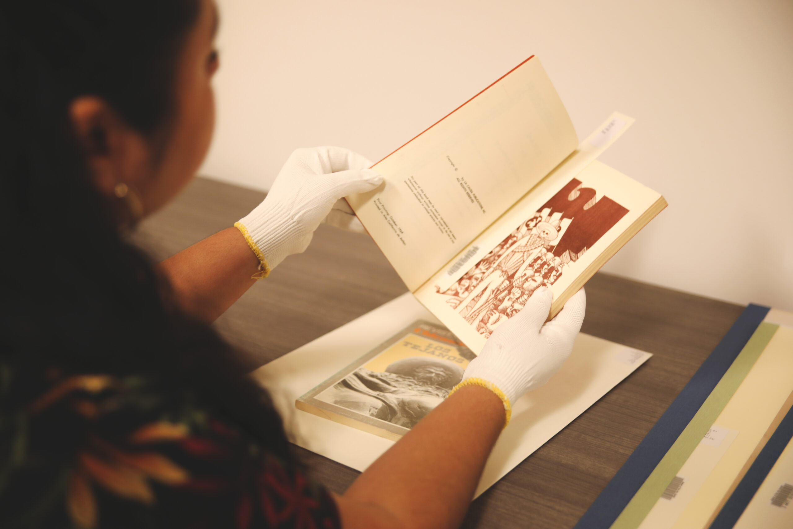 Person holds book open, with an image on recto and text on verso.