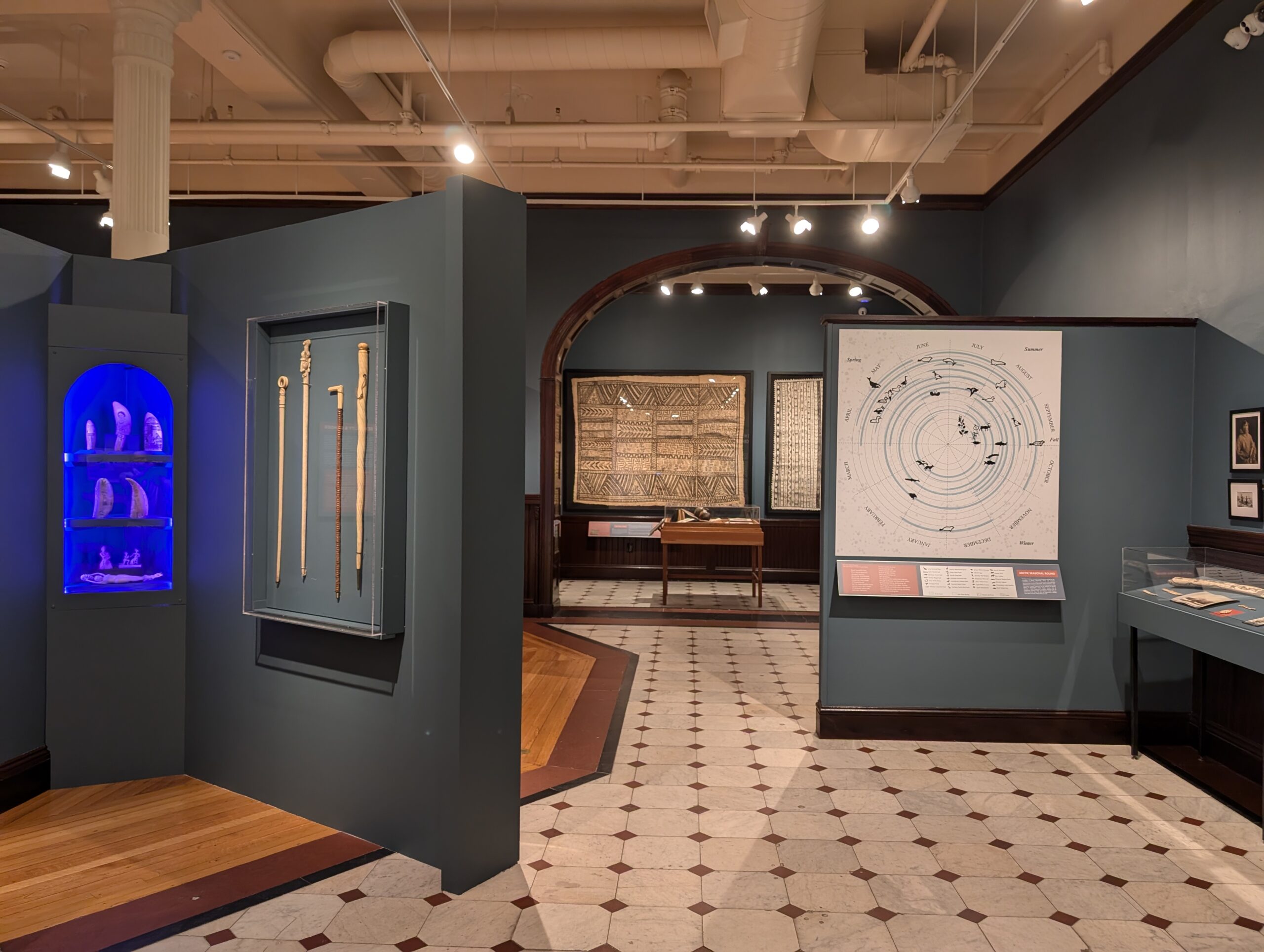 Objects hanging on gallery walls painted a dark gray-blue color.