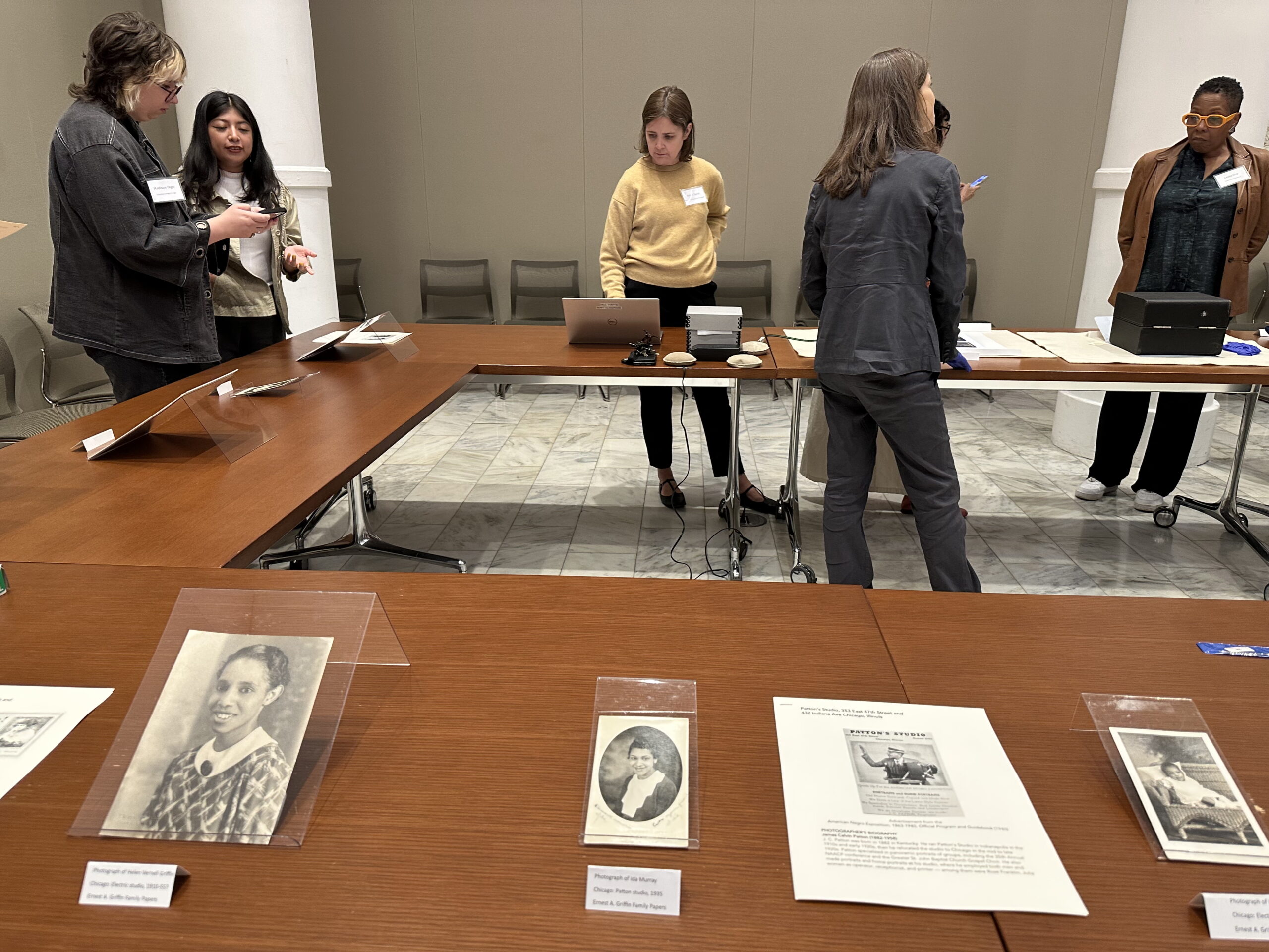 People standing around a "U" shaped table with various ephemera on it.
