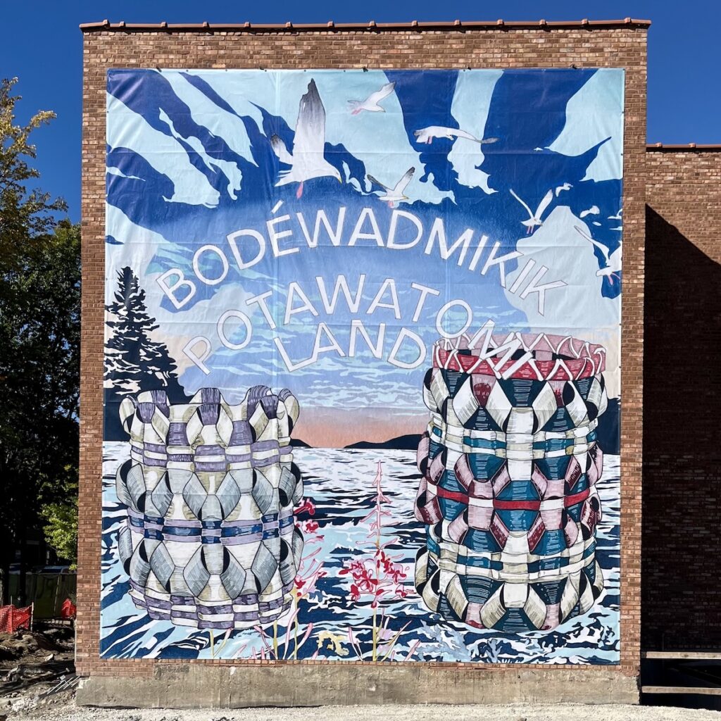 Large, multicolored mural installed on the exterior of a brown brick building.