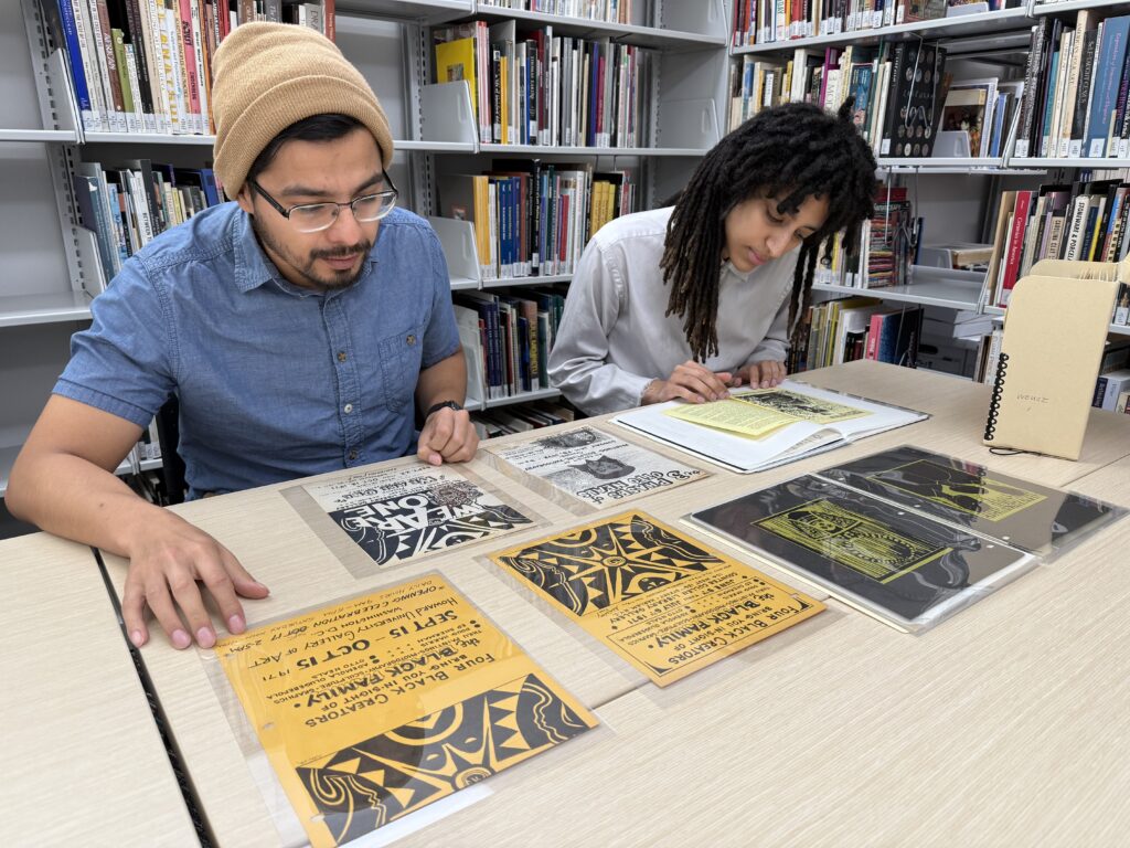 Two people seated at a table in a library reading archival material.