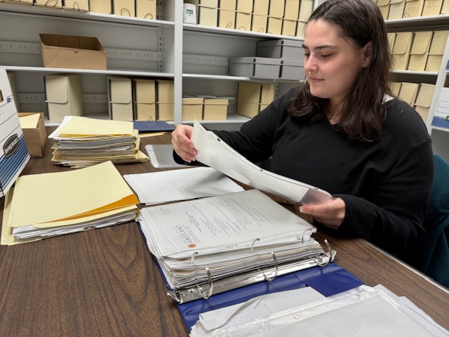 One person seated at a table in a library looking at archival material.