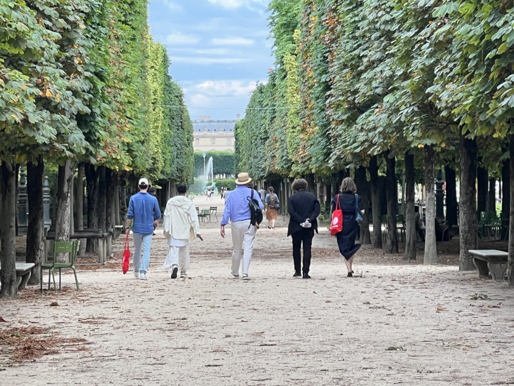 Five people walking in a park, their backs to the viewer.