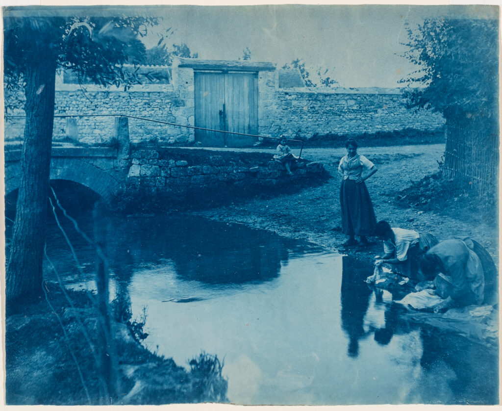 A cyanotype of three women by a river.